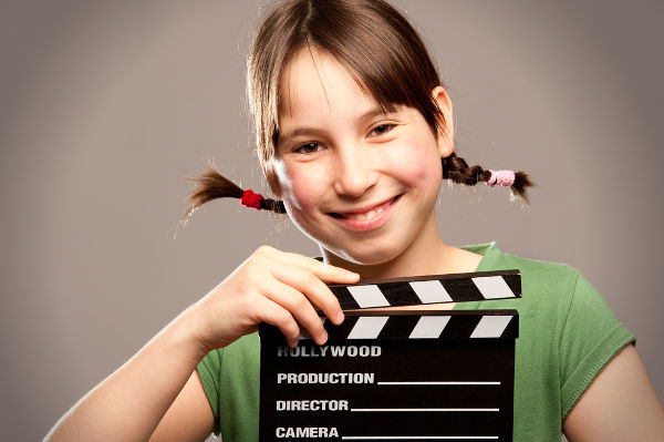 Young girl holding movie clapper board