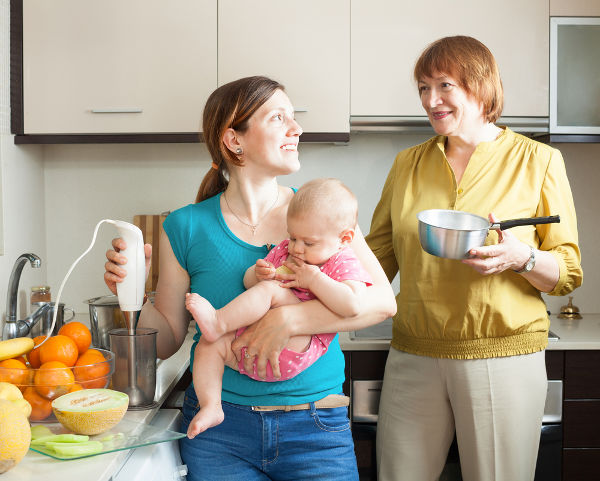 Happy women with child together cooking fruit puree