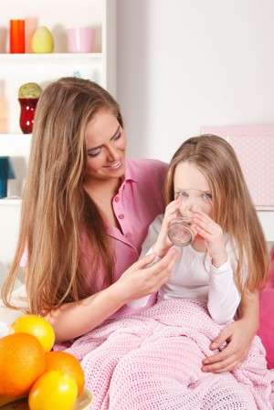 Sick girl drinking water with mum