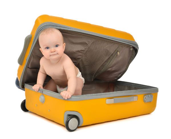 Happy infant baby toddler sitting in yellow plastic travel suitcase