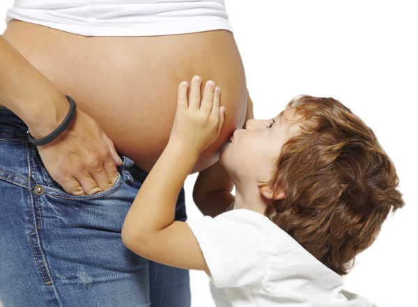 Young boy is kissing the pregnant woman