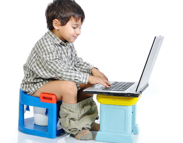 Cute kid sitting on toilet with laptop