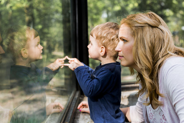 Beautiful woman holding her son with his reflection showing on the window