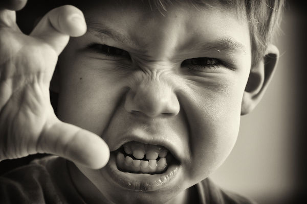 Black and white photo of a boy in an angry grimassy closeup.