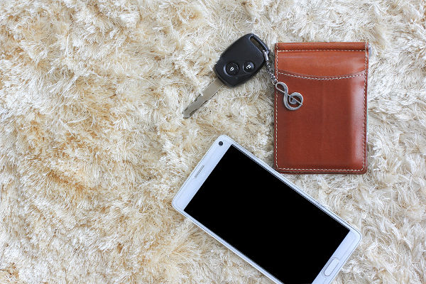 Mobile phone whit car key and brown wallet on brown shaggy carpet