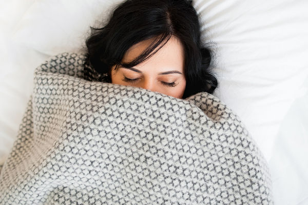 Sleeping woman cover face with blanket