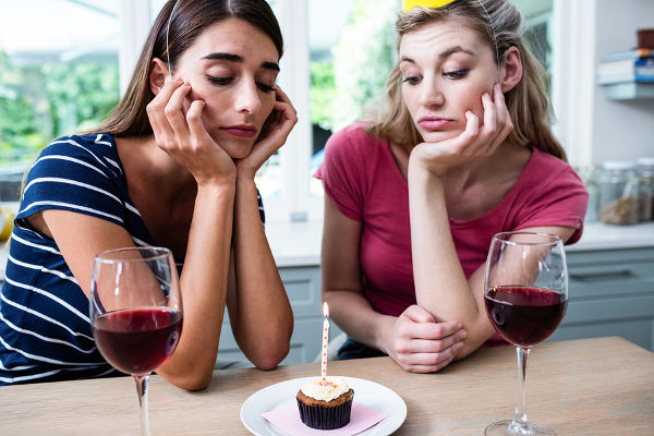Unhappy friends sitting at table during birthday party at home
