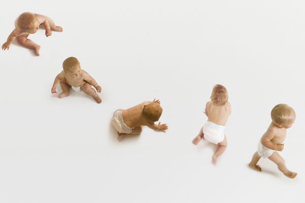 Row of babies sitting, crawling and walking on white background