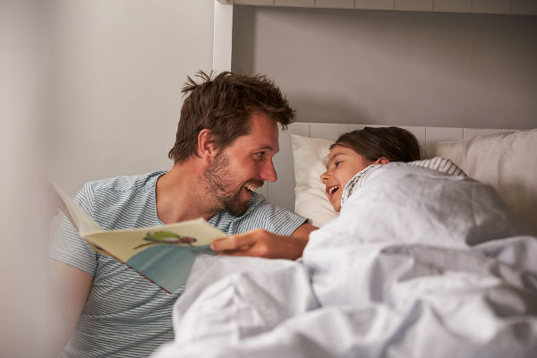 Father Reading Story To Daughter At Bedtime