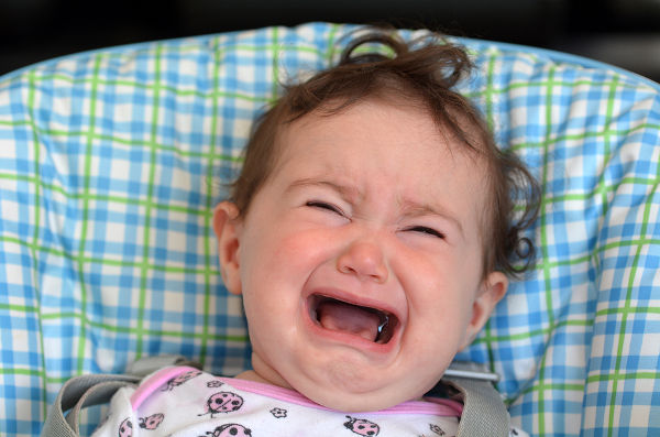 Little baby (girl age 6 months) scream and cry on a baby chair.