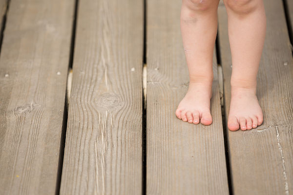 Closeup of child's bare feet on wooden floor. Toddler's legs and foot.