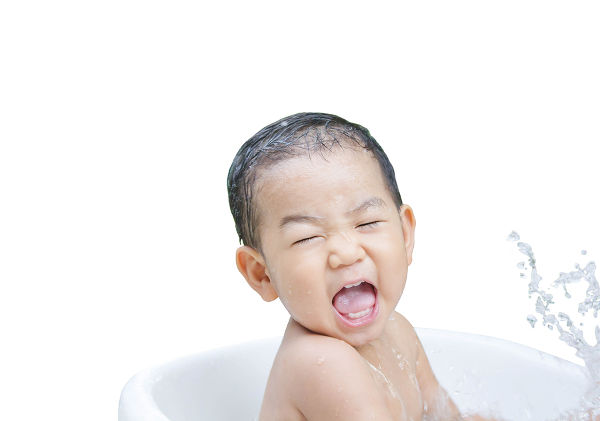 happy baby boy is bathed in white bath