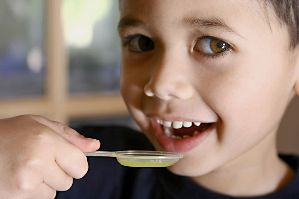 A young boy about to have his medicine in a spoon.