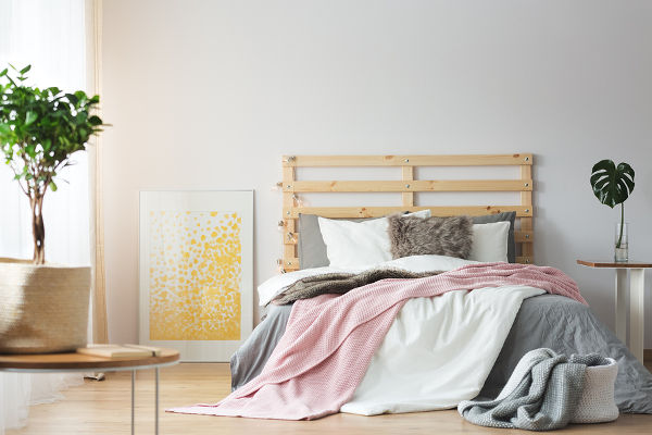 Messy bedding on wooden bed in cozy bright bedroom