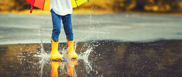 Feet of child in yellow rubber boots jump
