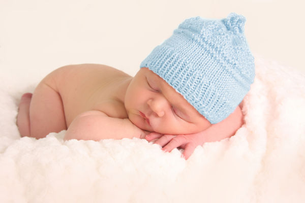 Newborn baby boy in a blue knitted hat.