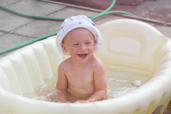 little boy in a white hat, bathing in an inflatable bath