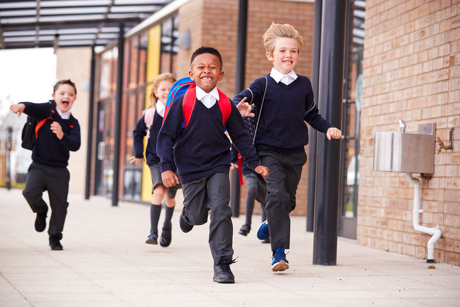 Happy primary school kids, wearing school uniforms and backpacks