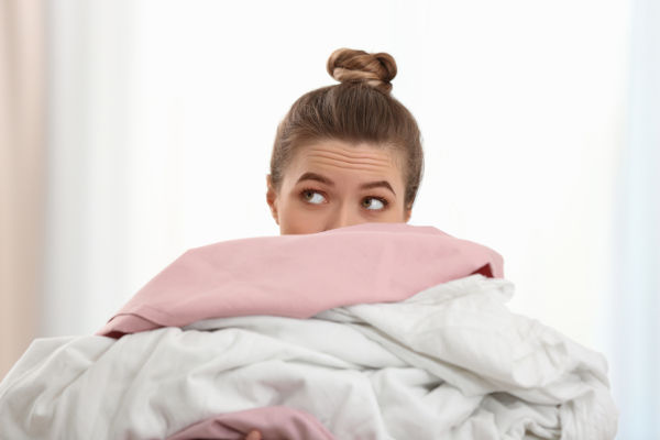 Woman Holding Pile Of Dirty Laundry Indoors