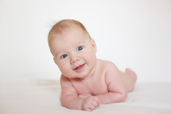 Three month old baby lying on tummy smiling