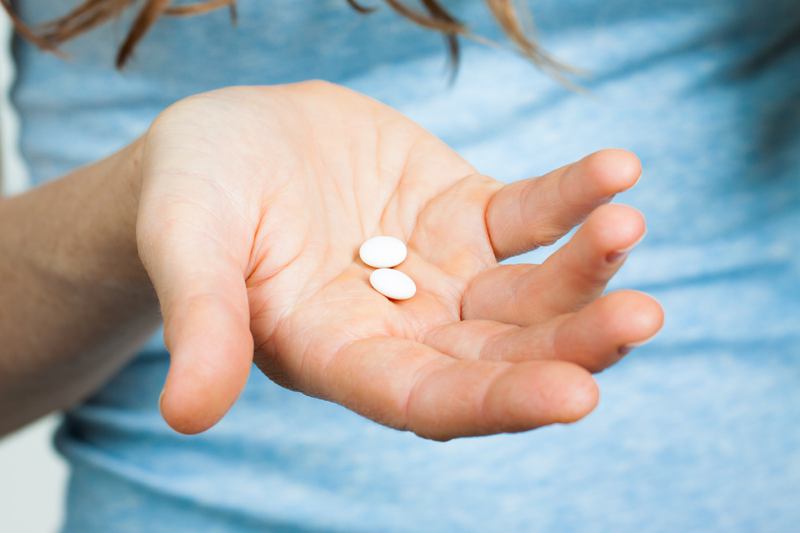 woman holding two white pills