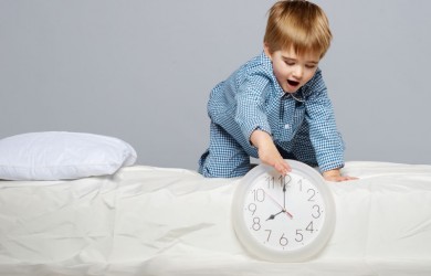 Little boy in bed with clock