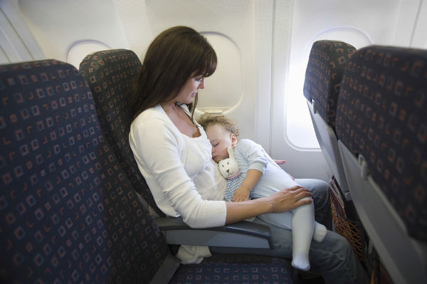 Toddler sleeping on mum in plane