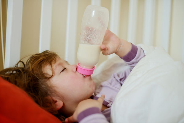 Toddler with bottle in bed