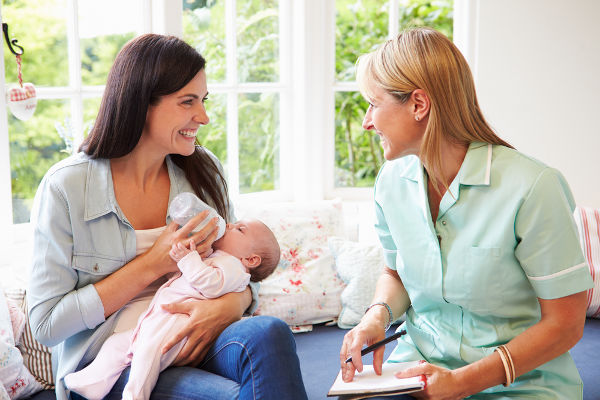 Mother With Baby Meeting With Health Visitor At Home