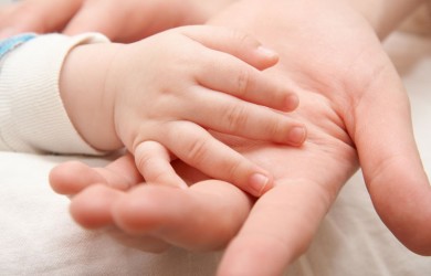 The hand of the child gently lays in a hand of mother