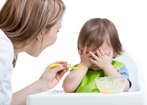 Mother trying to feed fussy toddler