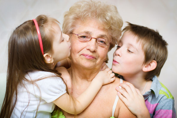 portrait of a cute grandchildren kissing grandmother