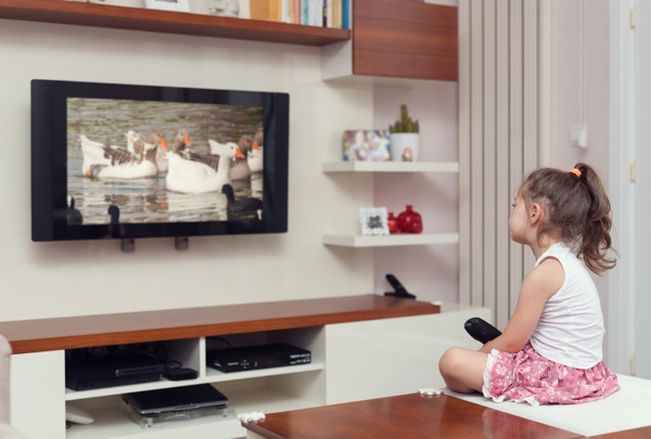 cute little girl having remote control and watching tv