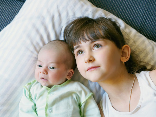 sister and baby brother lying together at home