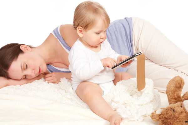 Child playing with your smartphone while mother is sleeping