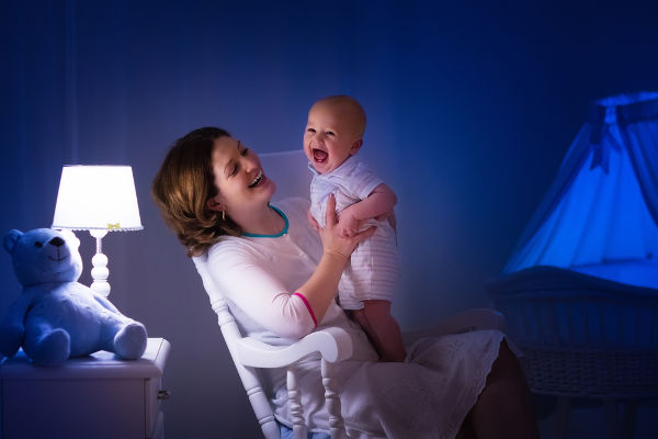 Mother and baby reading a book in dark bedroom