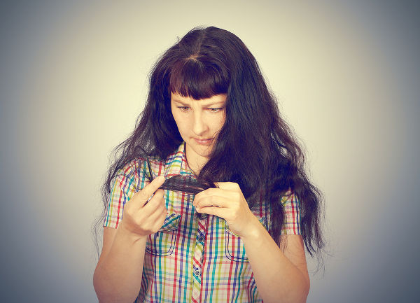 young woman looks at her problematic hair.