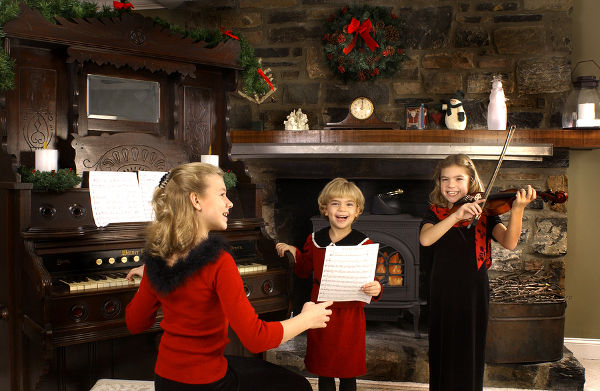 girls singing christmas carols in front of a fire.