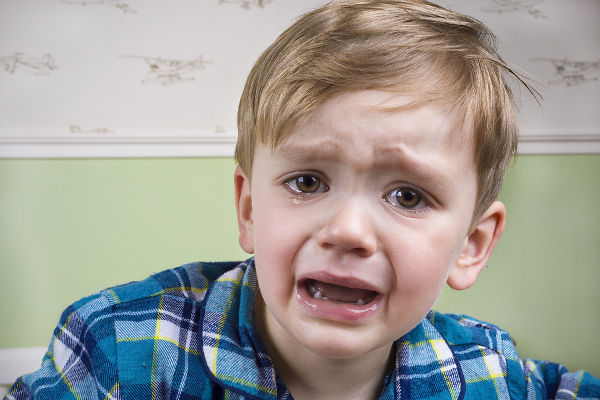 Small boy with big eyes crying dramatically before bedtime