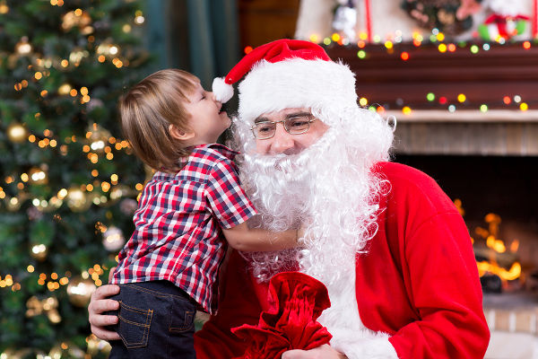 Santa Claus and child with presents at fireplace