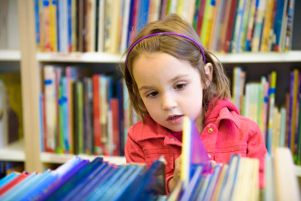 Little girl choosing book in library