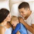 Caucasian mid adult parents with toddler son sleeping in bed.