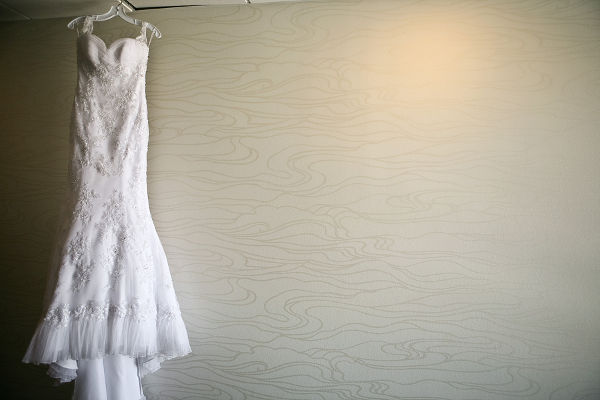 A white wedding dress hanging with a gray background