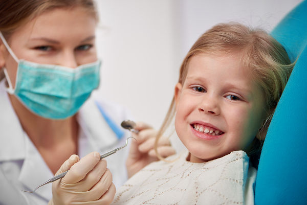 Happy smiling child sitting on dental chair ready to cure teeth