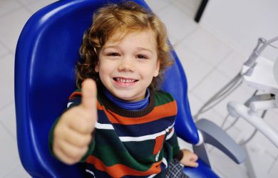baby boy with curly red hair in blue dental chair. Children's dentist