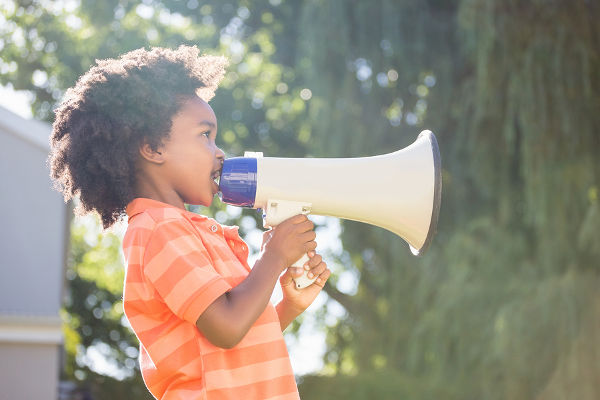 Cute mixed-race boy speaking on a megaphone on a park