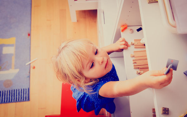 kids safety concept- little girl climbing on chair to get toy on top shelf