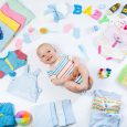 Baby on white background with clothing toiletries toys and health care accessories. Wish list or shopping overview for pregnancy and baby shower. View from above. Child feeding changing and bathing