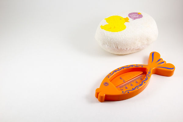 Baby sponge body and a thermometer for water on a white background