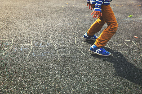 kid playing hopscotch on playground, kids outdoor activities